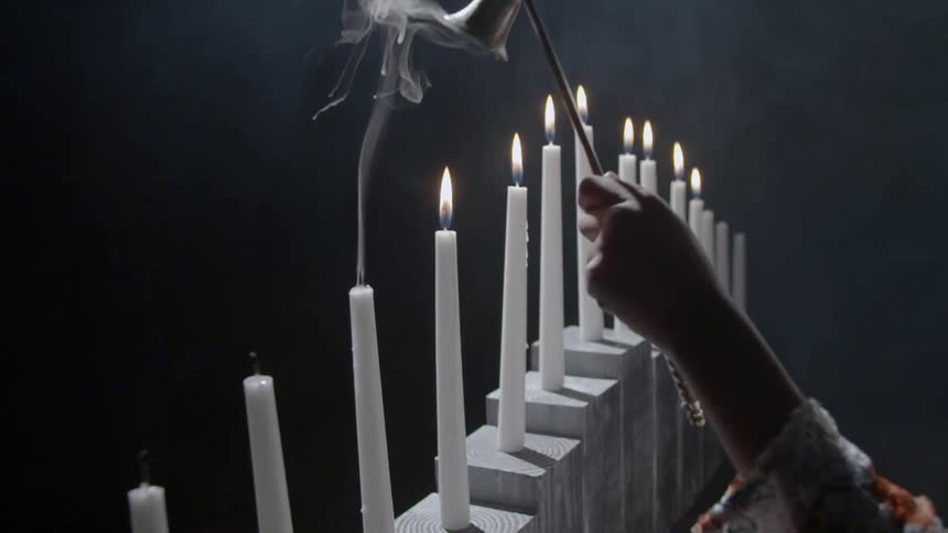 A person extinguishing a white candle as smoke rise from it