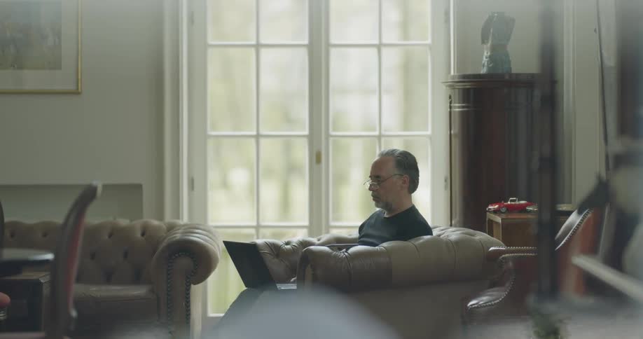 A man is sitting on the chair using his laptop