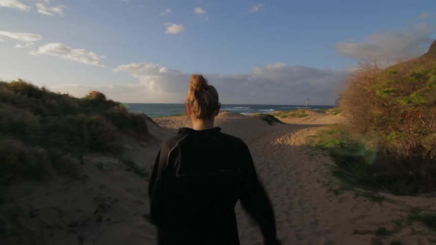 A woman is walking toward the beach