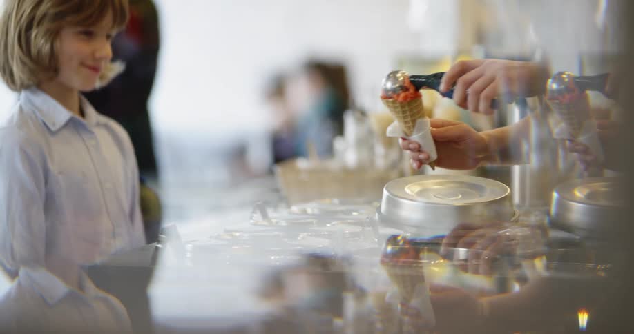 A child watches as an ice cream cone is scooped for him