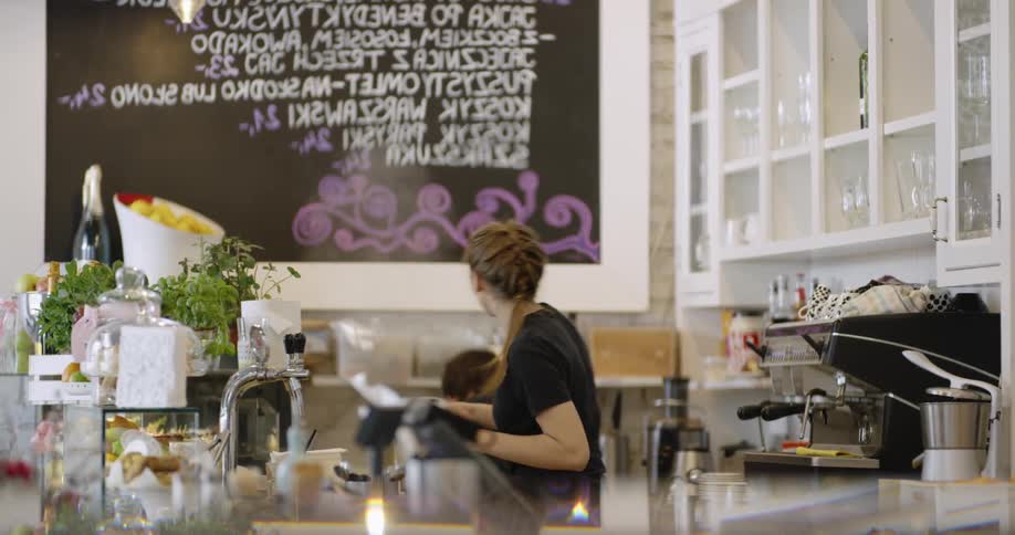 Two young people work behind a cafe counter together