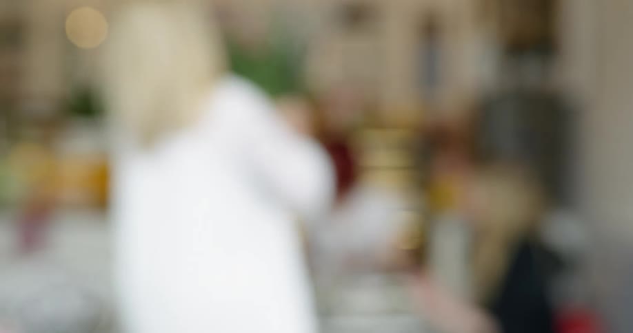 A woman picks up a vase of flowers and walks away with it