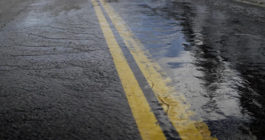Water flows over the yellow lines of a road