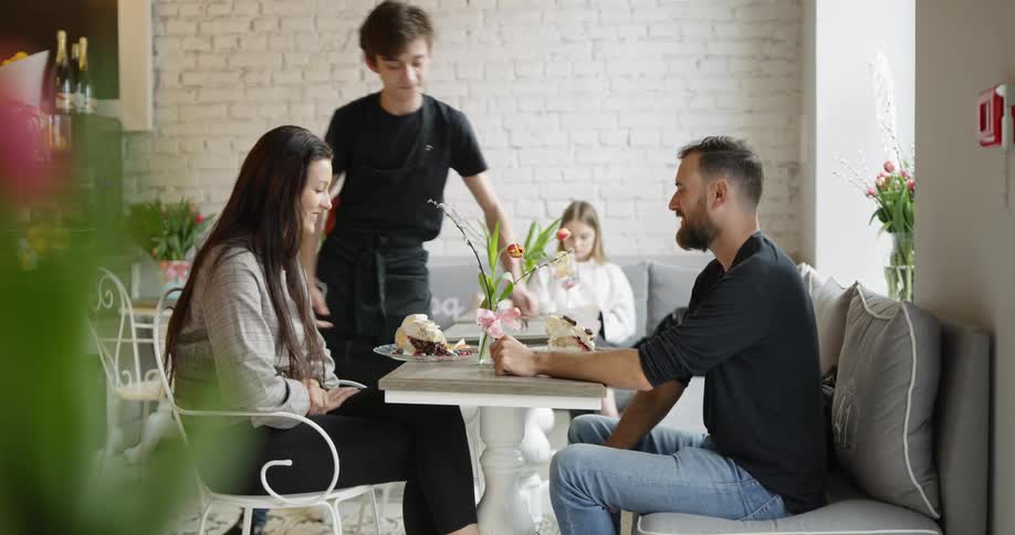 A man and woman are served dessert at a restaurant
