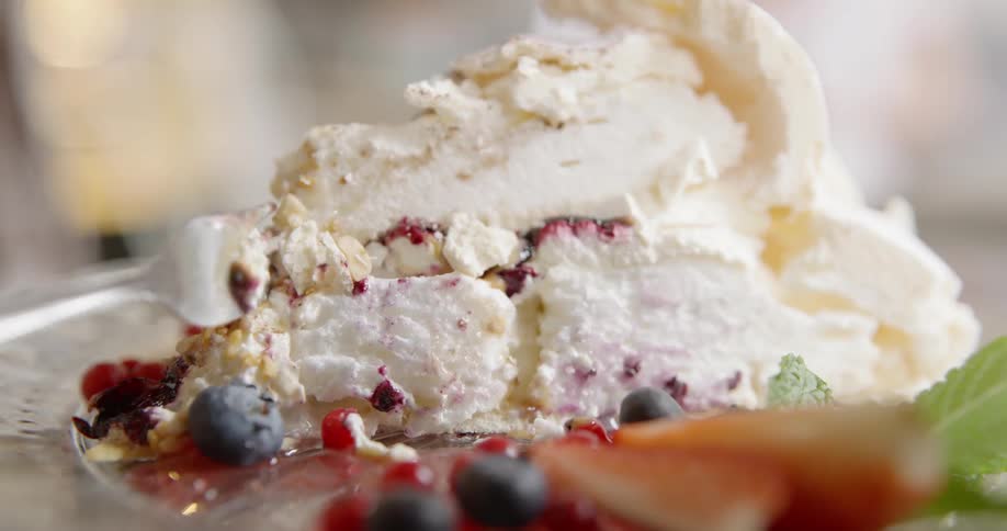 A person eats dessert from a glass plate with a metal spoon