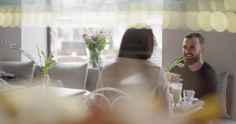 A man and woman smile over drinks and food at a cafe