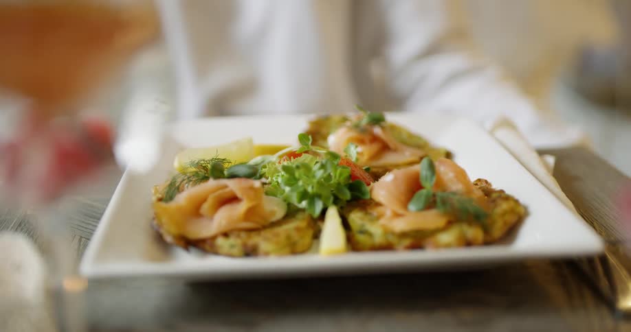 A person sets a plate of food down on a table for another person
