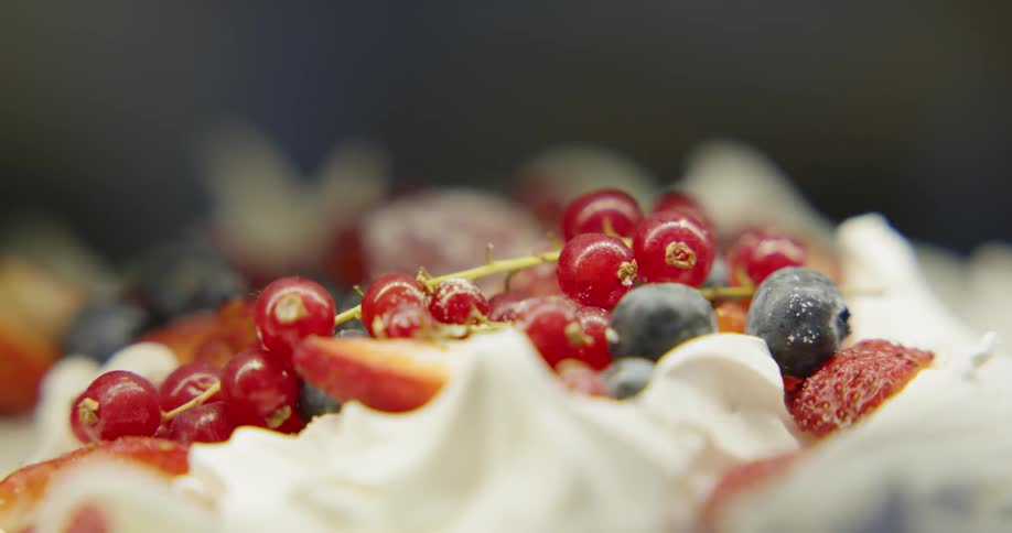 Mixed berries still attached to stem on top of whipped cream