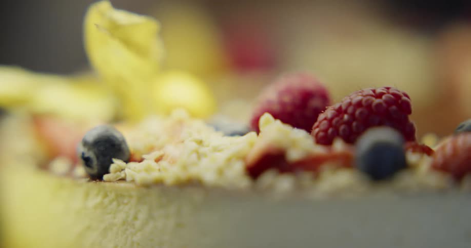 A pastry topped with raspberries and blueberries being pulled away from the camera