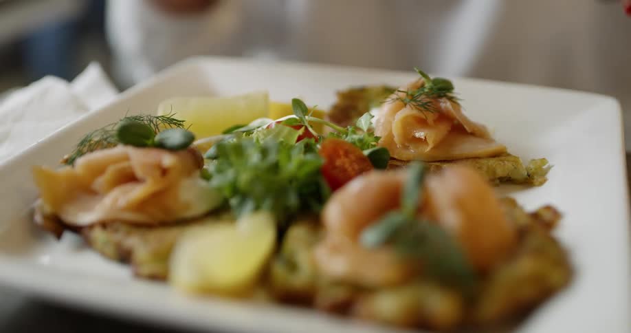 A person uses a knife and fork on a plate of food