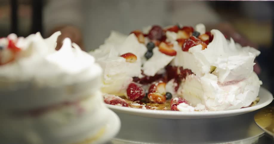 A person sets a fruit and cream cake on a table