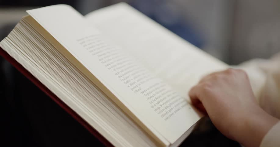 A womans hand holding a book and turning the page