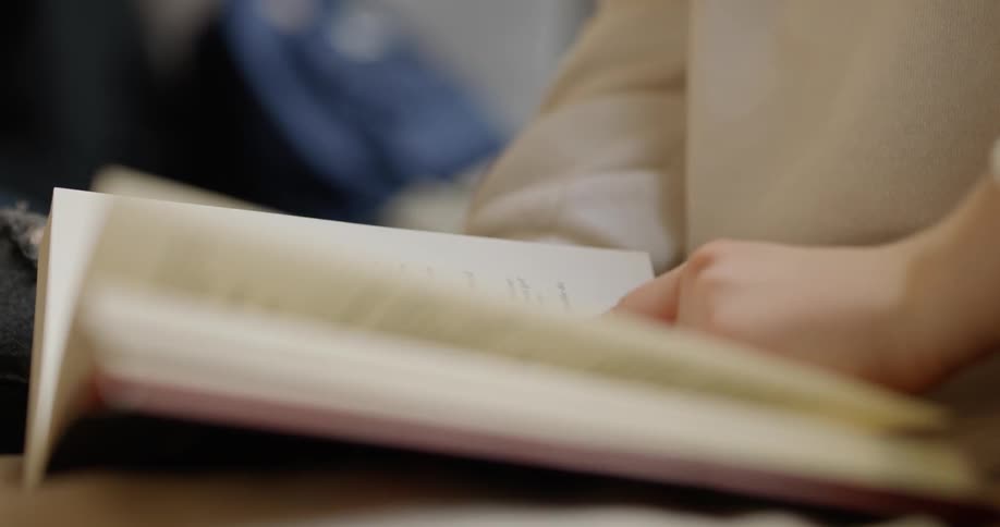 Woman flips pages of book indoors during daylight
