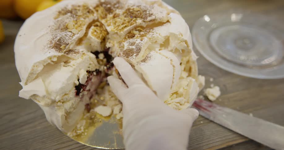 Person slices layer cake with a berry filling