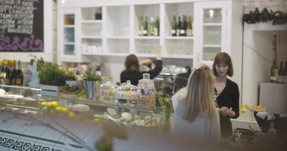 A woman approaching a counter in a cafe to give instructions to the worker behind it