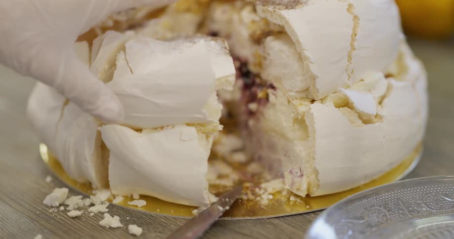 Person wearing gloves cuts into cake and serves piece