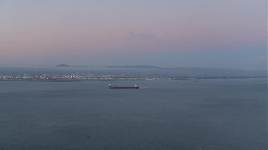 A ship sailing in the ocean with a town in the background