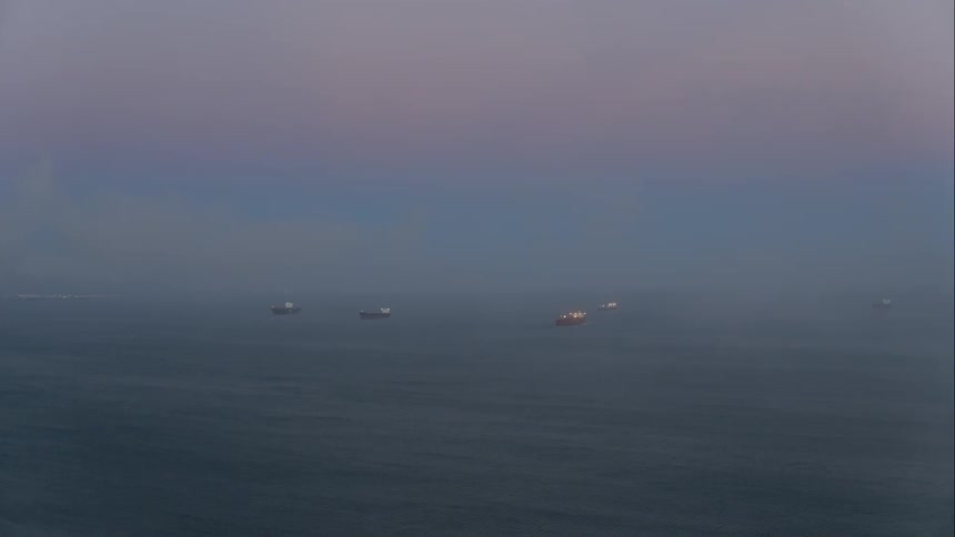 Boats sitting on a calm ocean under a dawn sky
