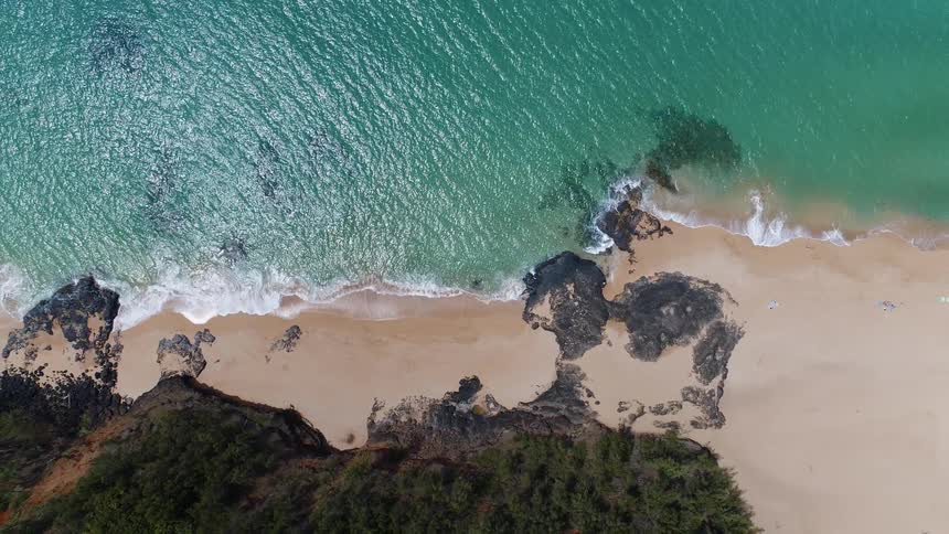 Waves crash on a sandy and rocky beach
