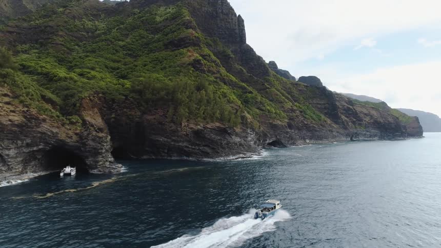 A boat driving near a mountain and cliffs