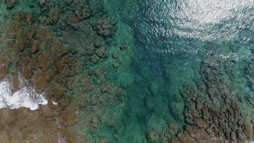 The blue water is crashing on the rocks