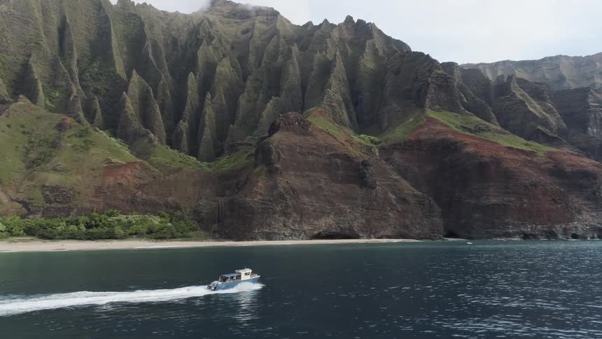 A boat goes across the water with the mountains in the background