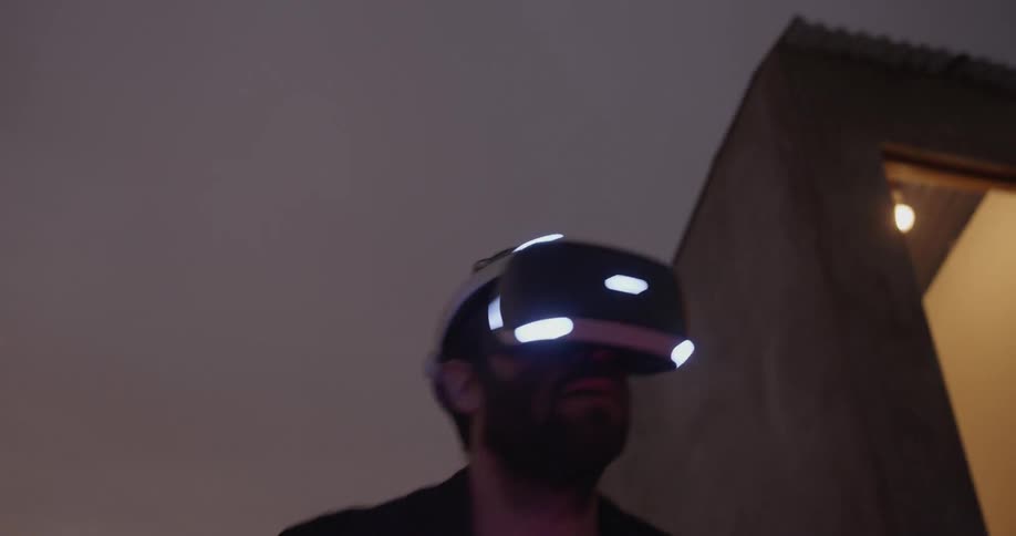 Male playing with virtual reality headset on the balcony at dawn