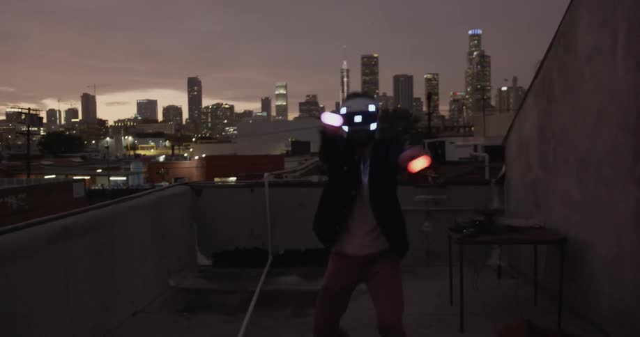 A young male playing with vr headset on the rooftop at dawn