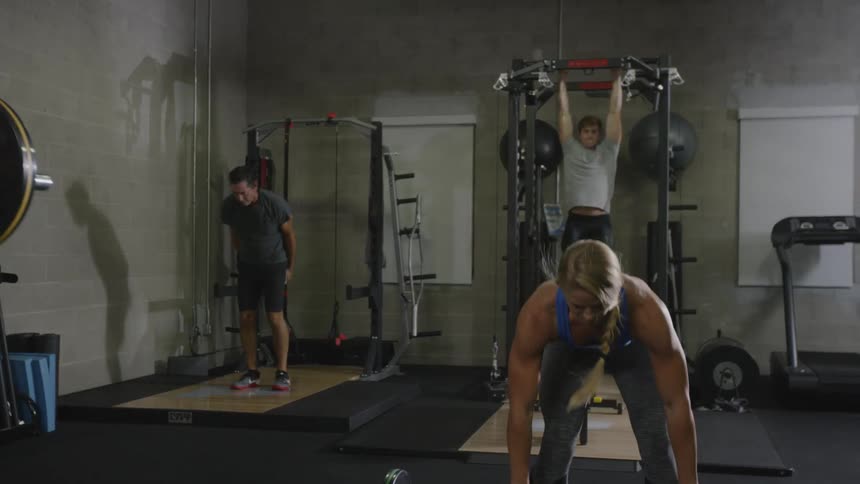 Buffed woman with blue tank top weight lifting at the gym