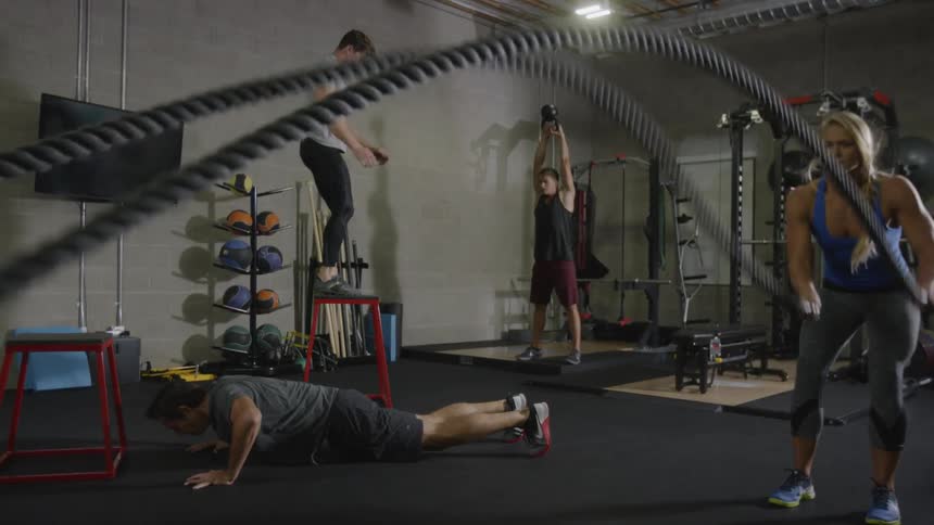 A muscular woman and three men work out in the gym