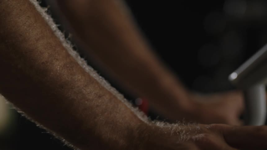 A mans arms are visible while he rides a stationary bike