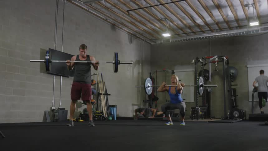 Three man and a woman work out in gym