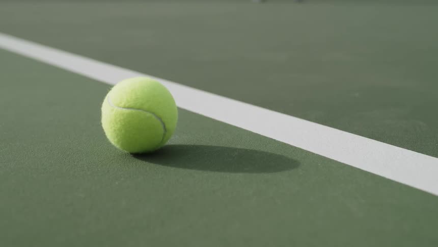 A tennis ball casts a shadow on a court