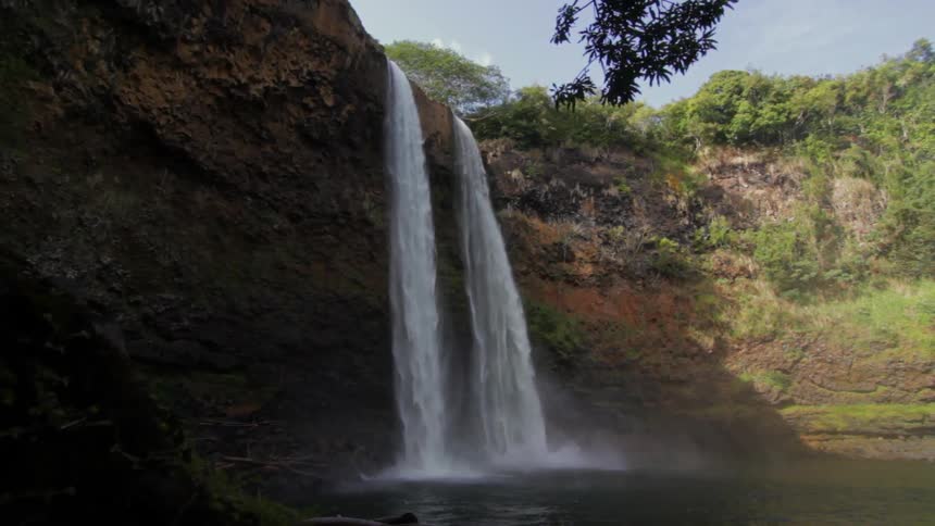 A waterfall near a tree covered cliff