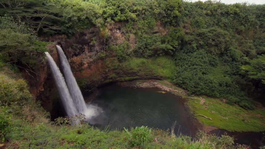 A waterfall on a rocky cliff pours into a basin