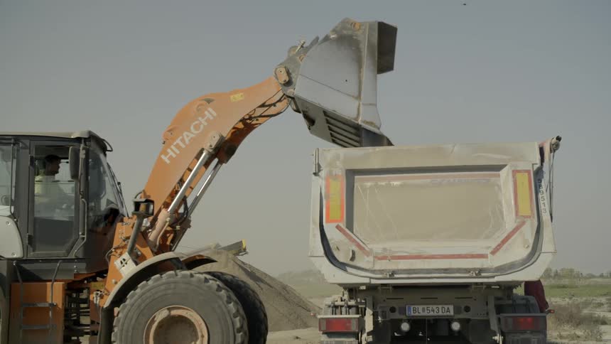 An excavator putting sand on the truck