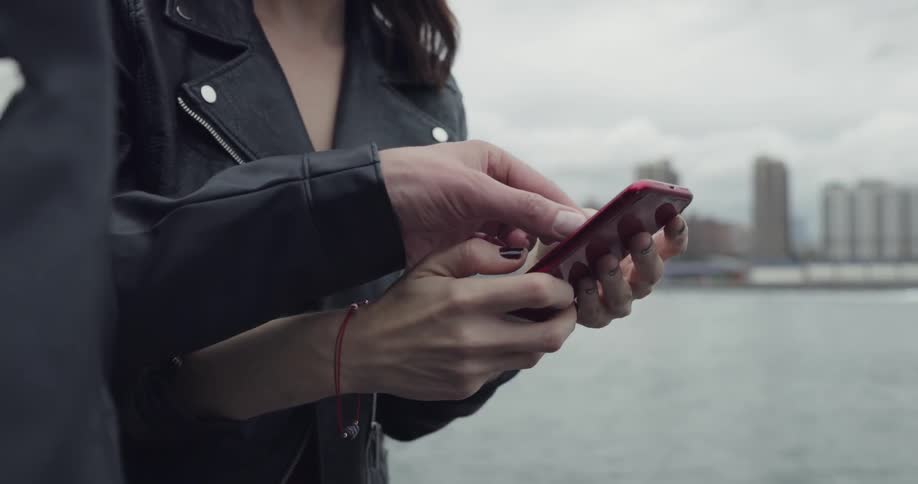 Woman takes a selfie with her smartphone and checks it out with man on a cloudy day