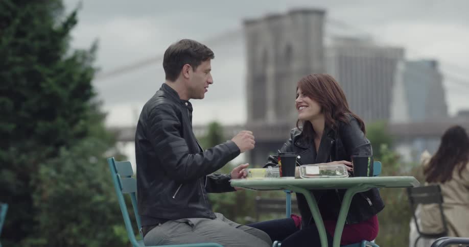 Man and woman are sitting outdoors at a table together