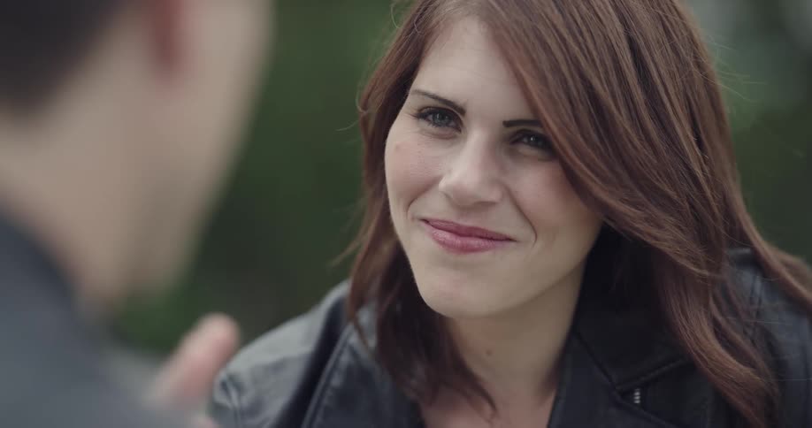 A young woman smiles and nods her head as she talks to a man