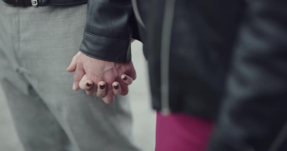 Man and woman wearing black leather jacket hold hands during daylight