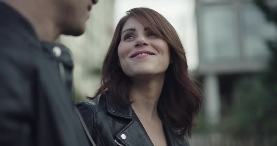 A woman smiles at a man and runs her fingers through her hair