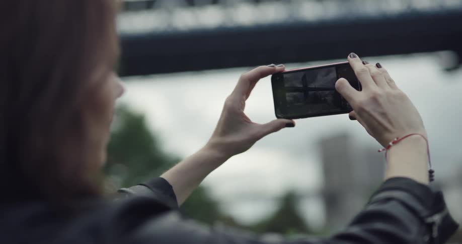 A woman takes a photograph of a bridge