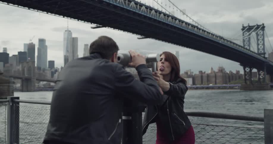 A man and woman are looking through a telescope at the city