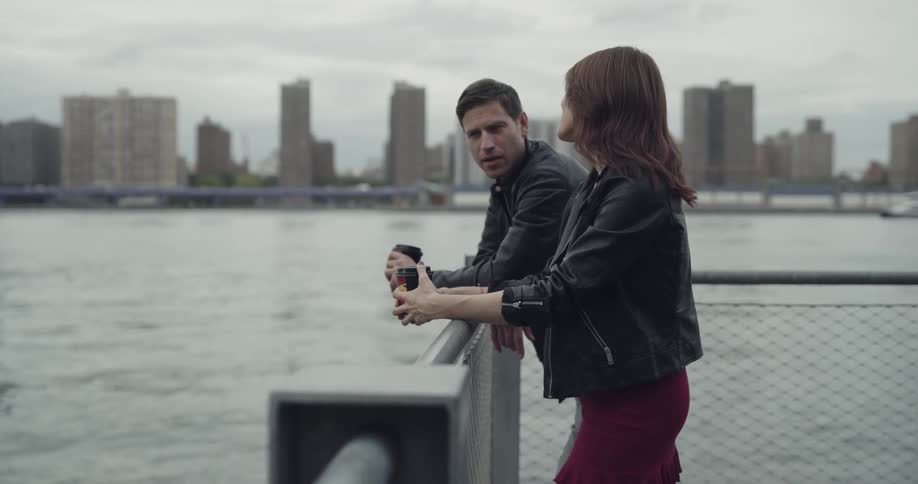 A male and female are outdoors talking by the ocean