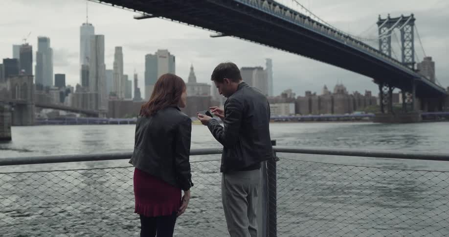 A man takes a photo of a bridge with a woman