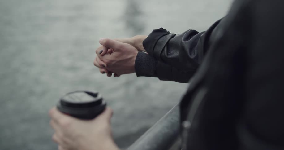Two people hold hands by the water