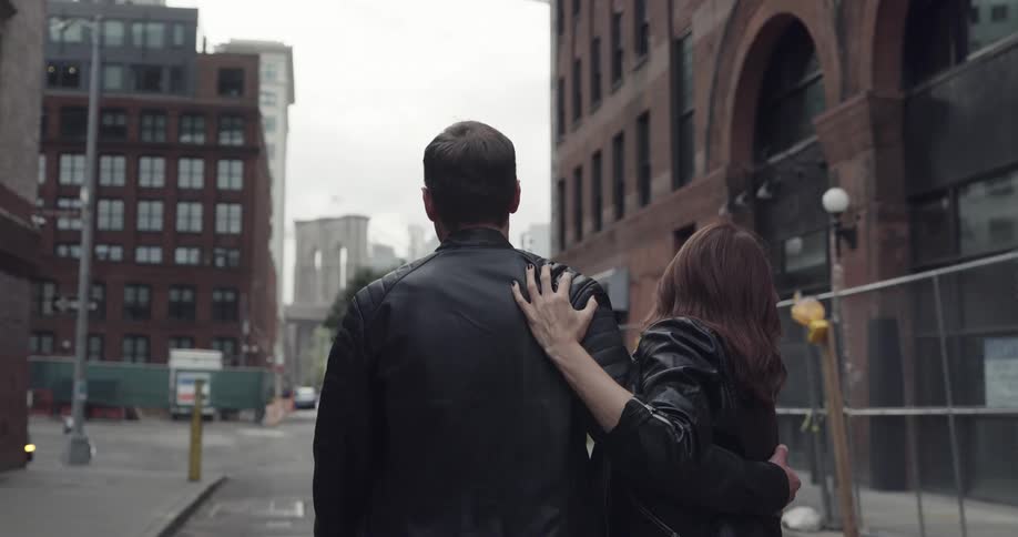 Man and woman embrace as they walk down a city street