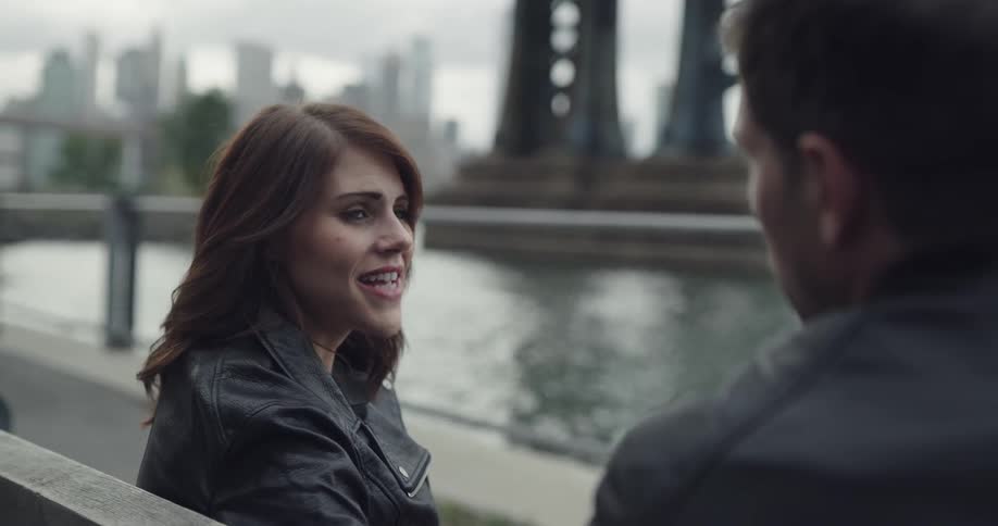 A couple talks romantically on the park bench near the river
