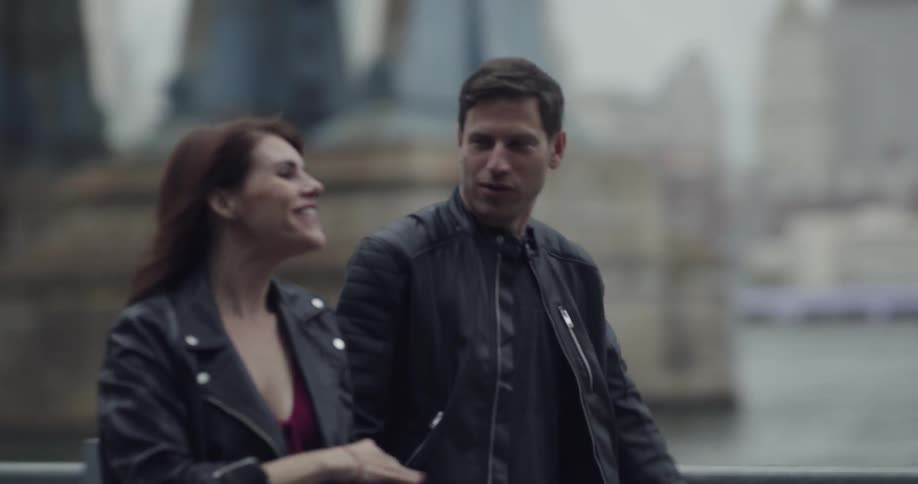 A man and woman in leather jackets walking down a pathway while holding hands