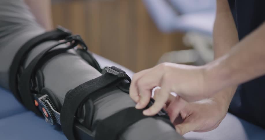 A persons leg brace is being removed by a therapist